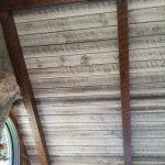 Close up of a ceiling with brown stained wood accent beams and a wood ceiling