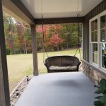 Close up of a new home's covered front porch with a brown wicker porch swing.