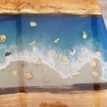 Close up of a wood island with a butcher block countertop and an ocean design with shells.