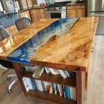 Close up of a wood island in a kitchen with book storage and a butcher block countertop with an ocean design.