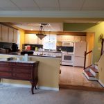 Photo of kitchen before remodel with lime green and yellow walls, white wood cabinets, and white appliances.