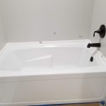 Close up of a white soaking tub with black faucets.