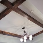 Remodeled home ceiling with exposed beams and a rustic 5-light chandelier.