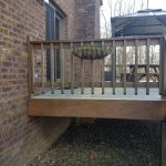 Close up of an old wood deck attached to a red brick home.