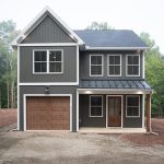 Front exterior view of a 2-story home with dark gray siding, white trim, a brown garage door, a covered front porch, and a brown front door.