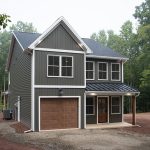 Front and left side exterior view of a 2-story home with dark gray siding, white trim, a brown garage door, a covered front porch, and a brown front door.