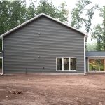 Right side exterior view of a 2-story home with dark gray siding, white trim, and a covered back patio.