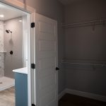 Closet with open white door leading into a bathroom.