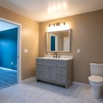 Bathroom with light gray and white flooring, brown walls, a white toilet, a gray sink vanity with white marble countertops, and a rectangle mirror.