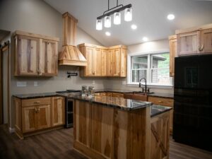 kitchen remodel with light wooden cabinets, black countertops, and black fridge